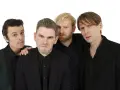 Les membres de Franz Ferdinand posent ensemble, quatre hommes aux regards intenses et aux coiffures stylées, prêts à enflammer la scène.