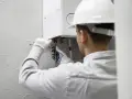 Tecnico con casco bianco lavora su una caldaia. Speriamo che la caldaia non faccia rumore di notte dopo l'intervento.