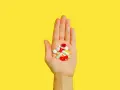 Hand hält bunte Pillen und Kapseln, die bei der Behandlung von Akne helfen könnten, wie z.B. Vitamin B5.