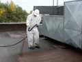 Pracownik w białym kombinezonie aplikuje preparat na dach. To ważny etap prac, by zapewnić trwałość i szczelność dachu, chroniąc go przed wilgocią. Styropapa to materiał, który wymaga fachowej aplikacji.