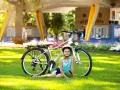 Dziewczynka w kasku odpoczywa obok roweru na trawie, gotowa na przygodę na szlaku EuroVelo 6.