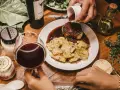 Elegancka kolacja z ravioli i wołowiną w sosie. Idealne pytanie: jakie wino do gotowania? Czerwone wino i świeże zioła dopełniają atmosferę.