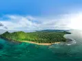 Zielona wyspa z palmami i plażą, otoczona turkusową wodą. Widok na Sao Tome z lotu ptaka.