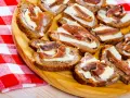 Na drewnianej desce ułożone są kromki chleba z masłem i anchois. To pyszne, proste przekąski.