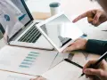 Analyse de rapports financiers sur tablette et ordinateur portable, illustrant la gestion administrative d'une entreprise.