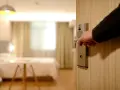 Otwieranie drzwi pokoju hotelowego, by wyłączyć światło i zadbać o oszczędzanie energii.