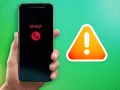 Hand hält Smartphone mit "SPAM"-Anzeige und rotem Hörer-Symbol. Daneben ein Warnzeichen. Call screening schützt vor unerwünschten Anrufen.