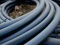 Coiled black hdpe plastic pipes with blue stripes, ready for installation.