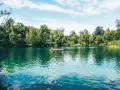 Zwei Personen entspannen auf einem Floß auf einem idyllischen Badesee im Schwarzwald.