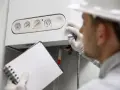 Tecnico con blocchetto e matita controlla la caldaia, sospettando una pompa caldaia bloccata.