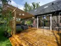 Trall med synliga skruvar kan vara en nackdel för utseendet. Här en altan med pergola, utemöbler och solrosor.