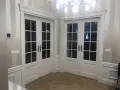Eleganckie białe drzwi dwuskrzydłowe z przeszkleniem, osadzone w metalowych futrynach, tworzą stylowe przejście.