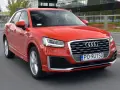 Czerwone Audi Q2 w ruchu miejskim. Choć jego design jest atrakcyjny, warto rozważyć potencjalne wady, takie jak ograniczona przestrzeń bagażowa.