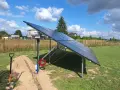 Nowa instalacja fotowoltaiczna w granicy działki, gotowa do podłączenia. Obok koparka i materiały.