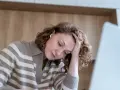 Kobieta z problemami z koncentracją opiera głowę na dłoni, patrząc w dół.
