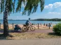 Mężczyzna na rowerze z przyczepką jedzie ścieżką rowerową wzdłuż plaży. To idealne miejsce na wycieczkę trasą pogoria 3.