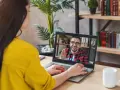 Kobieta na wideo rozmowie z mężczyzną, który uśmiecha się i macha. Może to być konsultacja online, np. test na autyzm.