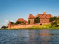 Potężny zamek w Malborku nad rzeką. Zwiedzanie zamku w Malborku to podróż w czasie.