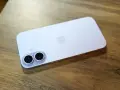 A light purple iPhone with a dual-camera system lies on a wooden surface.
