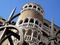 La Torre del Bovolo, con la sua architettura a chiocciola e i suoi loggiati, si staglia contro il cielo azzurro, vista attraverso un cancello in ferro battuto.