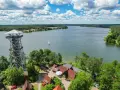 Wieża widokowa nad jeziorem Wyrówno, z której rozpościera się widok na spokojną taflę wody, żaglówkę i otaczający las.