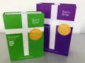 Zwei "Basis Bibel" Ausgaben, eine grüne und eine violette, mit dem Aufdruck "NEU Altes + Neues Testament". Diese evangelische Bibel ist so gestaltet, dass sie leicht verständlich ist.
