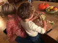 Zwei Kinder helfen im Haushalt und schneiden Blumenkohl. Ein Kürbis und Obst liegen daneben.