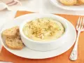 Deliciosa brandada de merluza cremosa, gratinada con piñones y pan rallado, servida con tostas.