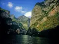 Navegando por el **río Yangtsé**, rodeado de imponentes acantilados verdes y un cielo azul con nubes.