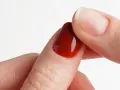 Dettaglio di un'unghia con smalto gel rosso intenso, perfetta per un tutorial unghie gel principianti.