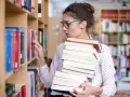 Młoda kobieta z okularami, z pasją do książek, pracuje w bibliotece. Nawet bez formalnego wykształcenia, jej miłość do literatury pozwala jej odnaleźć się w tym miejscu.