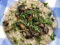 Risotto cremoso con champiñones salteados y perejil picado en un plato azul a cuadros.