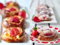 Pyszne drożdżówki z truskawkami, posypane cukrem pudrem, kuszą swoim wyglądem i zapachem. Idealne na deser lub śniadanie.