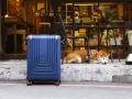 En blå resväska står redo för en resa utomlands. En söt shiba inu vilar bredvid, som om den också väntar på att packa sin packlista utomlands.