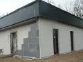 Budowa domu ze styropianu w trakcie. Widoczne bloczki, okna i dach przykryty czarną folią.