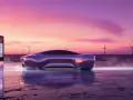 Futurystyczna Tesla przy ładowarce na tle zachodu słońca. Zastanawiasz się, ile kosztuje ładowanie Tesli w domu?