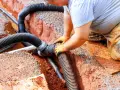 Instalator łączy rury odprowadzające wodę do budowanej studni chłonnej.