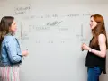 Dos mujeres discuten un diagrama en una pizarra, mostrando varios tipos de pizarras y el viaje del desarrollador.