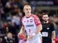 Młody zawodnik w białej koszulce z orłem i numerem 4, gotowy do rzutu piłką ręczną.