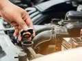 Hand removing radiator cap. This image might be relevant when researching radiator hose replacement cost.