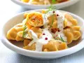 Pierogi z farszem, polane sosem, udekorowane koperkiem i pieprzem.