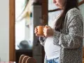 Ciepły napar z rooibos w dłoniach ciężarnej kobiety. Delikatny dym unosi się z kubka, tworząc chwilę spokoju.