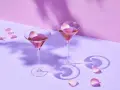 Elegancki French Martini przepis: dwa kieliszki z różowym drinkiem, ozdobione płatkami róż, na pastelowym tle.