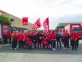 Un gruppo di lavoratori BRT, con bandiere rosse, manifesta per migliorare le condizioni di lavoro. Le loro opinioni su lavorare in Bartolini sono chiare.