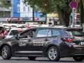 Ein dunkler Uber-Kombi steht im Stau. Die Aufforderung "Jetzt die App downloaden" ist gut sichtbar.