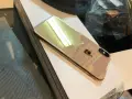 Błyszczący, złoty iPhone X leży na białej powierzchni.