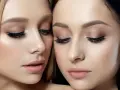 Dwie kobiety z perfekcyjnym makijażem glamour. Delikatne cienie na powiekach, długie rzęsy i subtelnie podkreślone usta tworzą efektowny, ale naturalny look.