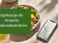 Aplikacja do liczenia makroskładników ułatwia przestrzeganie diety keto. Obok talerza z sałatką leży smartfon z widocznym interfejsem aplikacji.