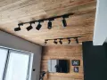 Nowoczesne reflektory na szynach, idealne jako oświetlenie, które przykleić na sufit. Drewniany sufit i ściana tworzą przytulną atmosferę.