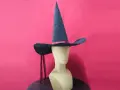Un mannequin porte un patron chapeau pointu bleu foncé avec un ruban rouge. Deux rubans rouges pendent de chaque côté.